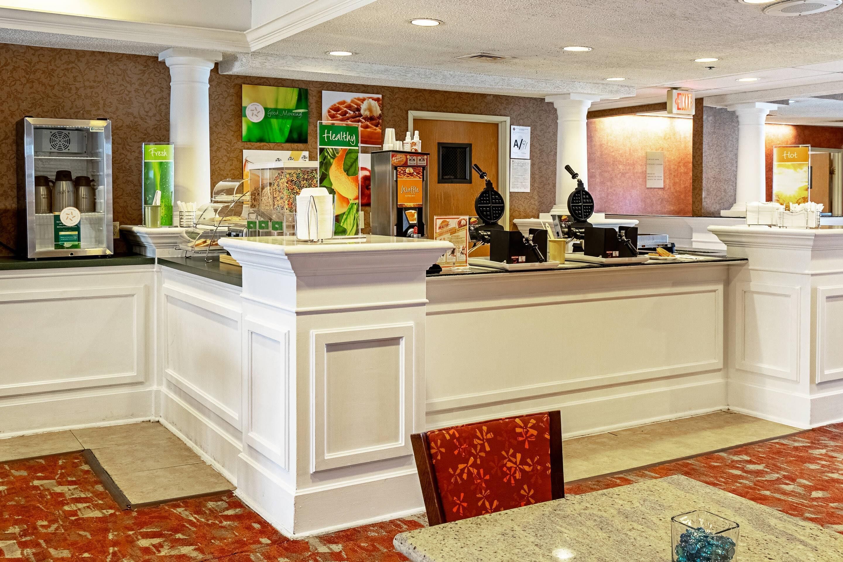 A hotel reception area with a counter, coffee machines, and a waffle maker.
