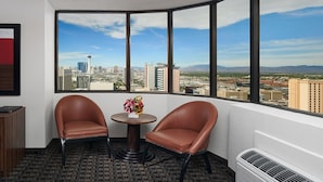 Ein Eckzimmer mit zwei Ledersesseln, einem kleinen Tisch mit Blumenvase und einem großen Fenster mit Blick auf die Stadt.