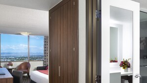Ein Hotelzimmer mit Bett, Schreibtisch, Stuhl, Badezimmer mit Spiegel und Blick auf die Stadt.