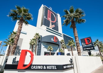 A reception area with a red counter, a large wall with abstract art, and a TV mounted on the wall. at the D Las Vegas