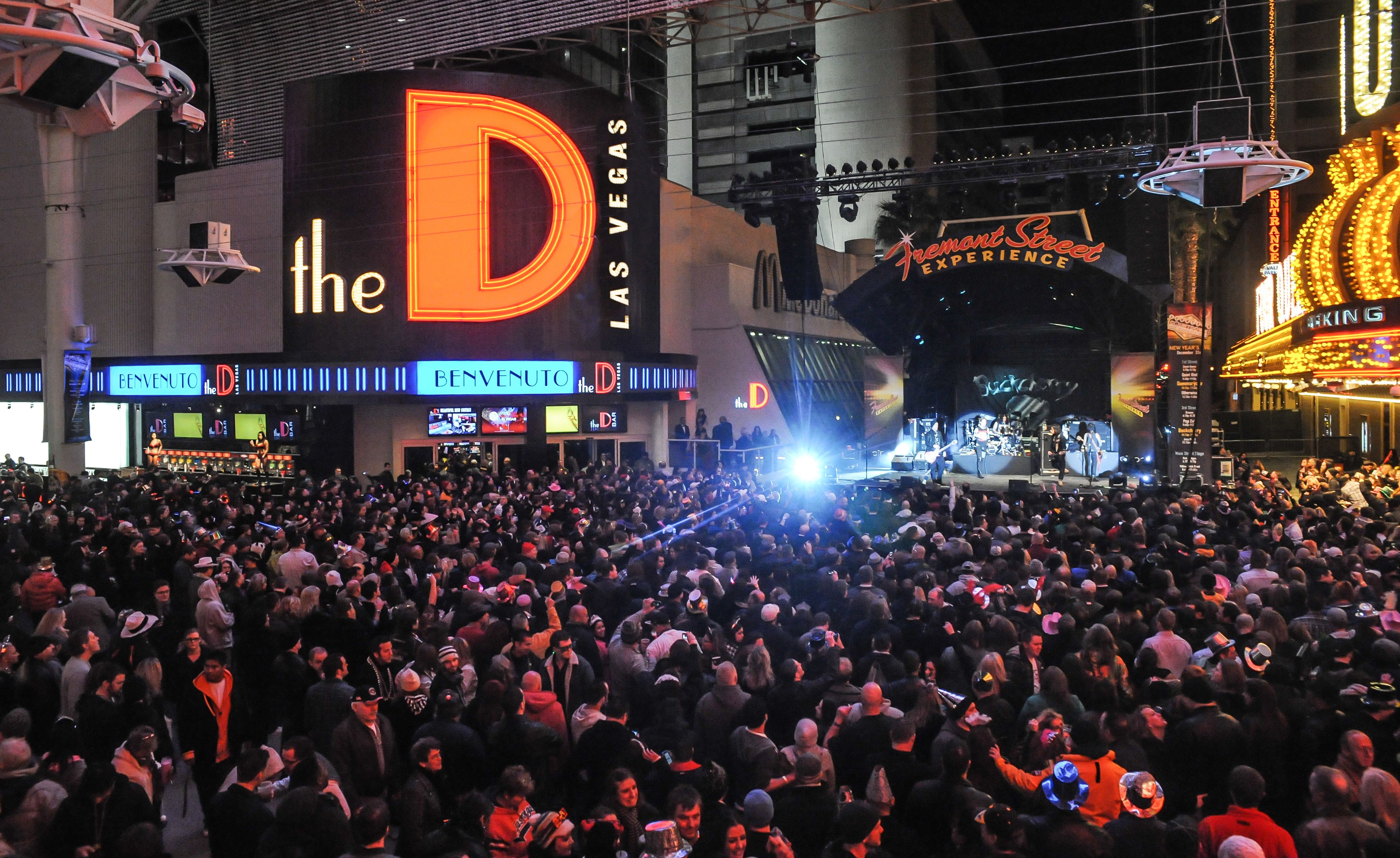 A crowded scene at a Las Vegas entertainment venue with a large stage and bright signage.