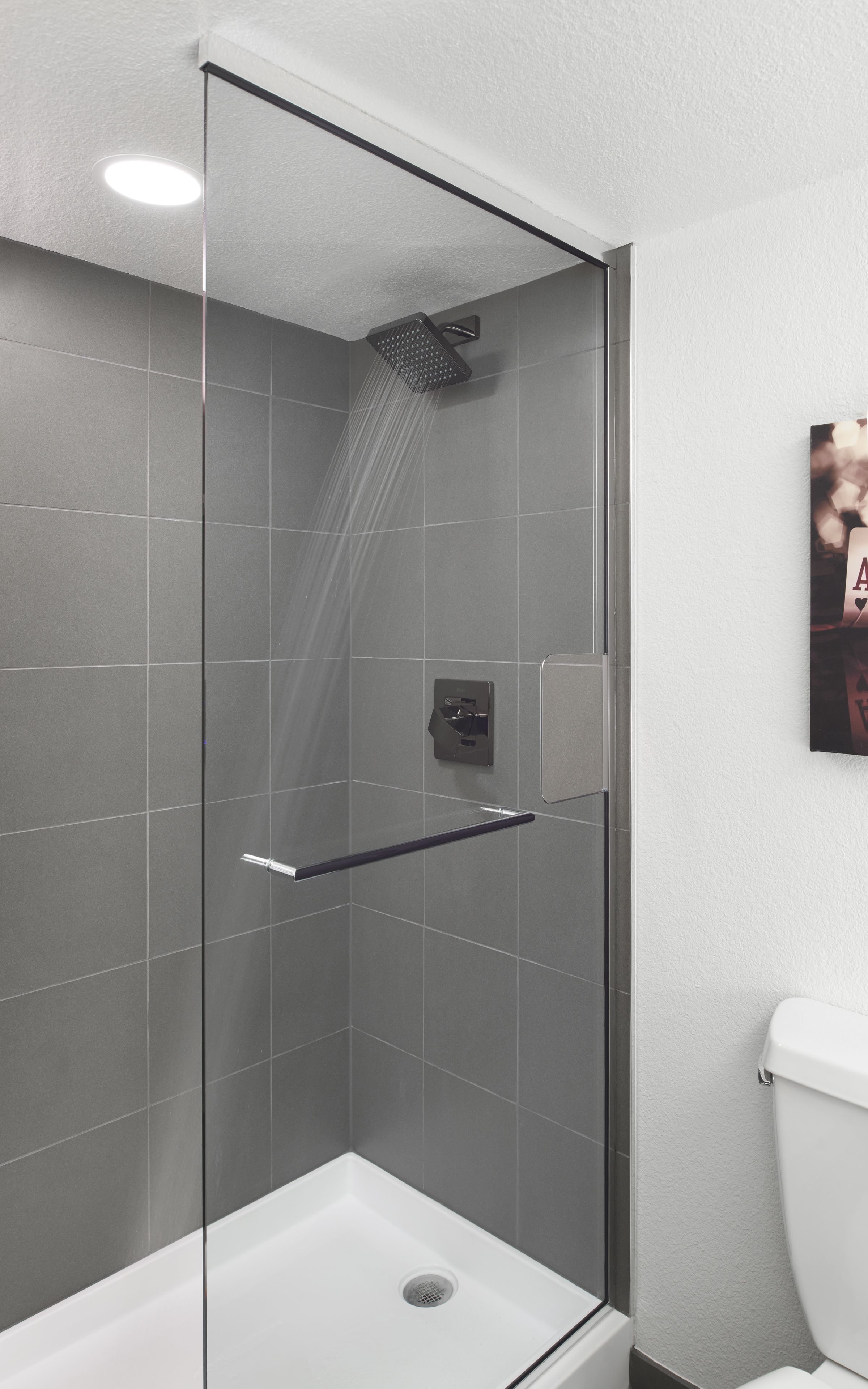 Een moderne douchecabine met een glazen deur, een handdouche en een bedieningspaneel.