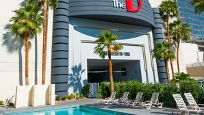 Ein Hotel mit einem gut sichtbaren 'D'-Logo, einem Pool und Palmen.