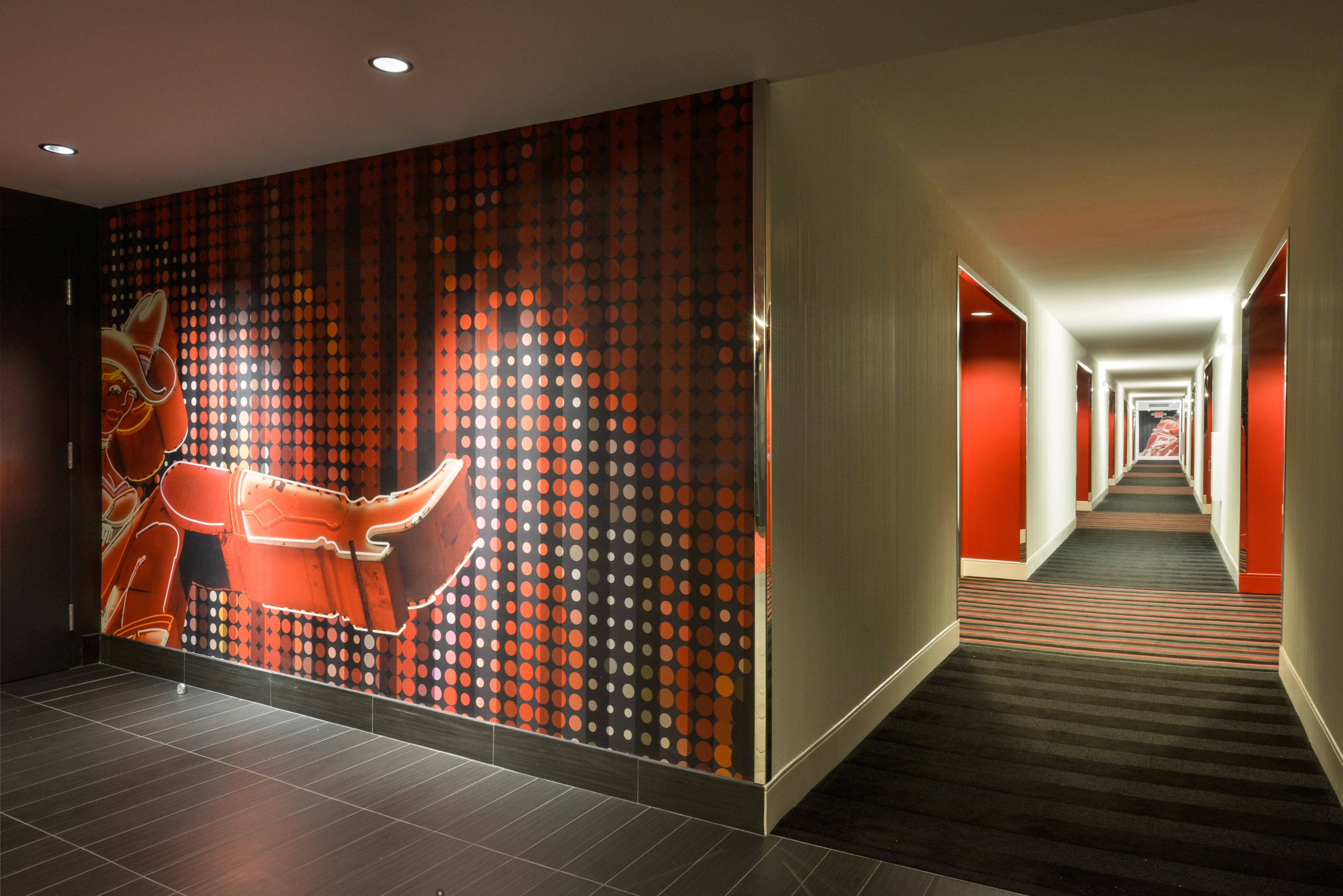 A hotel hallway with a patterned wall, a carpeted floor, and a long corridor.