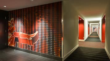 A hotel hallway with a patterned wall, a carpeted floor, and a long corridor.