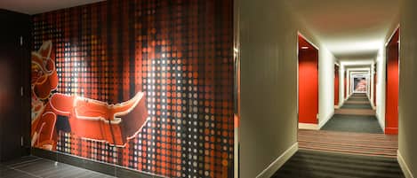 A hotel hallway with a patterned wall, a carpeted floor, and a long corridor.