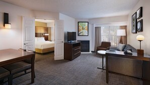 A hotel room with a bed, a desk, a chair, a TV, a fireplace, and a window with curtains. - Residence Inn by Marriott Austin The Domain Area (Austin)