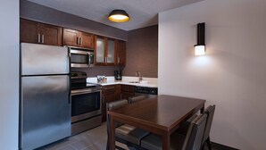 A modern kitchen with stainless steel appliances, wooden cabinets, and a dining area with a table and chairs. - Residence Inn by Marriott Austin The Domain Area (Austin)