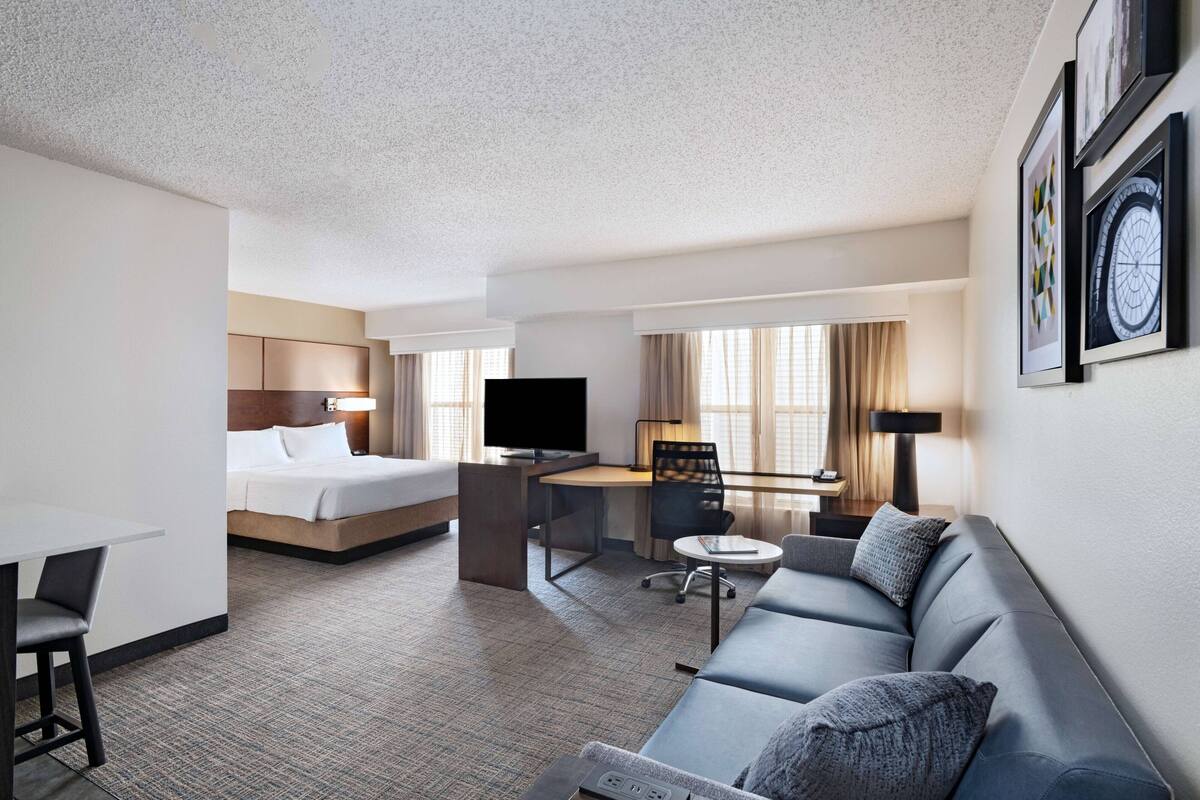 A hotel room with a bed, a desk, a sofa, and a TV.