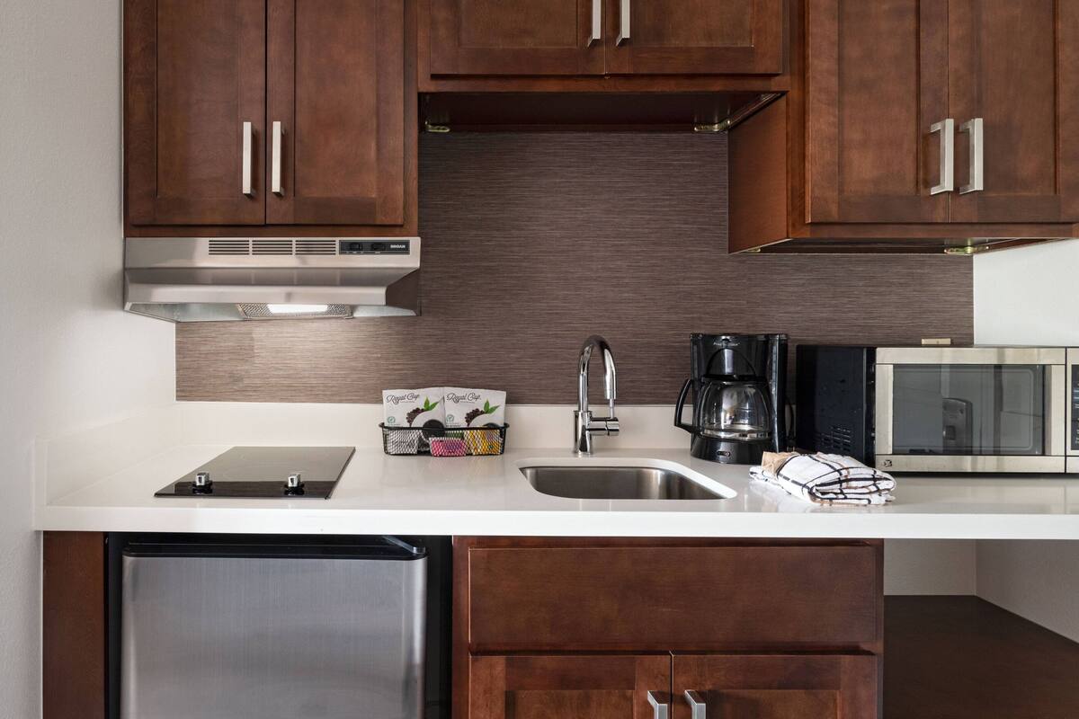 A modern kitchen with wooden cabinets, stainless steel appliances, and a white countertop.