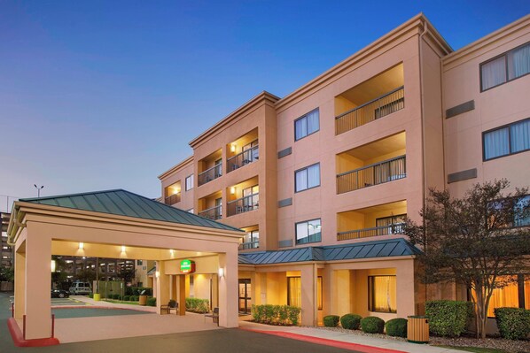 A multi-story hotel with a covered entrance, multiple balconies, and a well-lit facade.