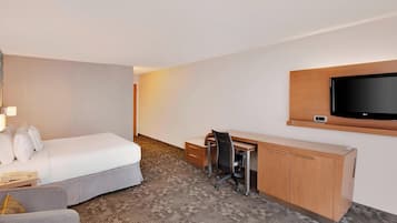 Una habitación de hotel con una cama, un escritorio, una silla, un televisor y un armario.
