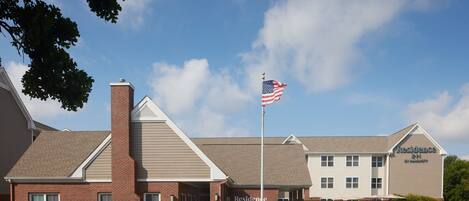 A brick building with a flagpole, a sign for 'Residence Inn by Marriott', and a clear blue sky.
