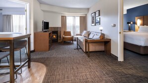 Ein Hotelzimmer mit Bett, Schreibtisch, Sofa, Fernseher und Kamin.