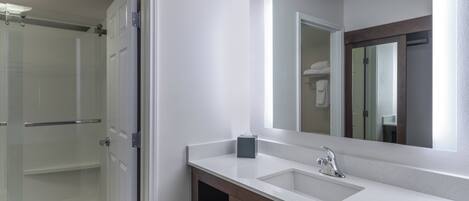 Une salle de bain moderne avec une douche à parois de verre, un lavabo blanc avec un miroir au-dessus et un porte-serviettes.