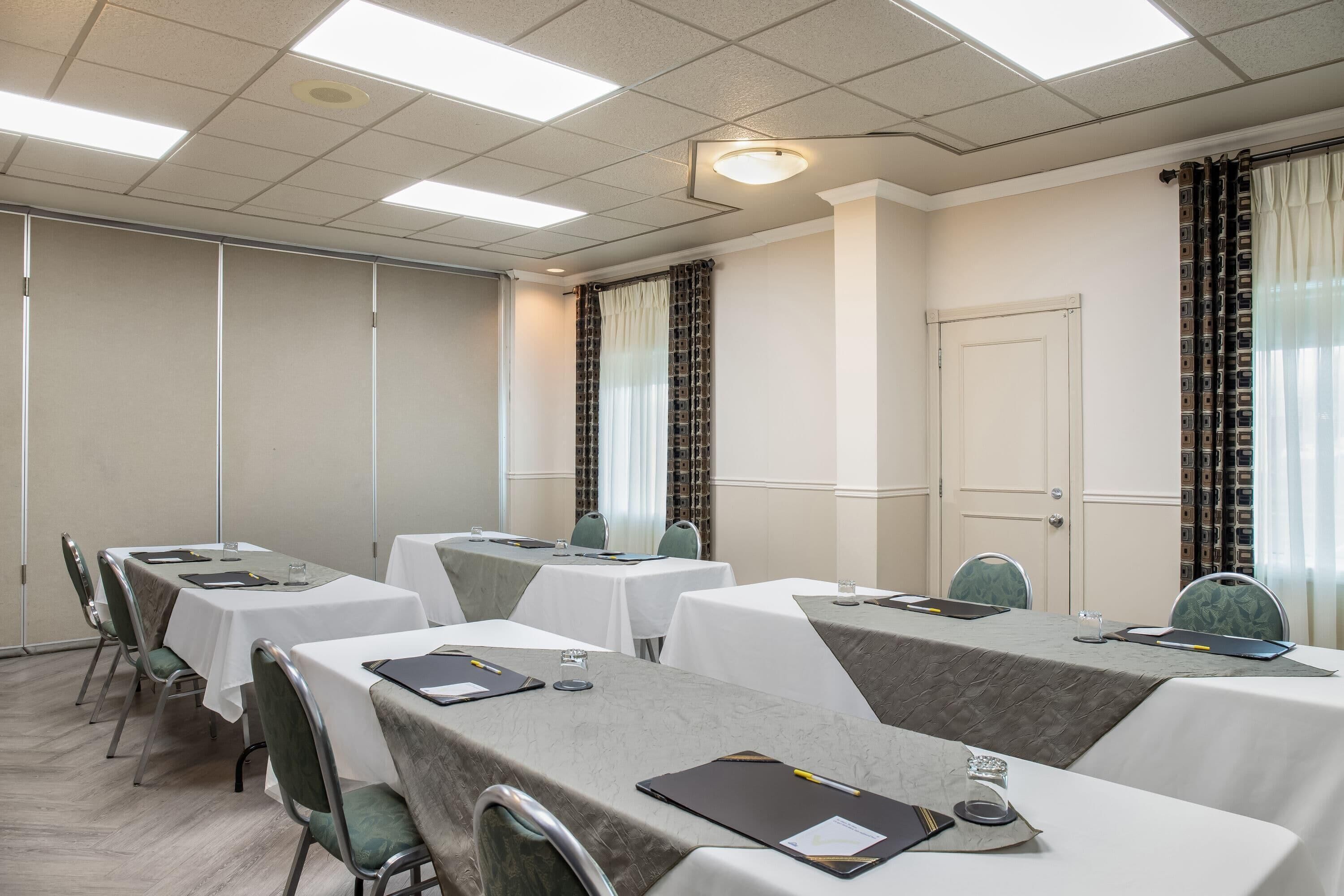 A conference room with multiple tables, chairs, and a door.