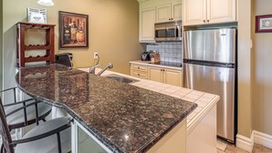 Una cocina con encimeras de granito, electrodomésticos de acero inoxidable y armarios de colores claros.