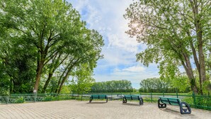 Un parque con tres bancos verdes y un sendero pavimentado.