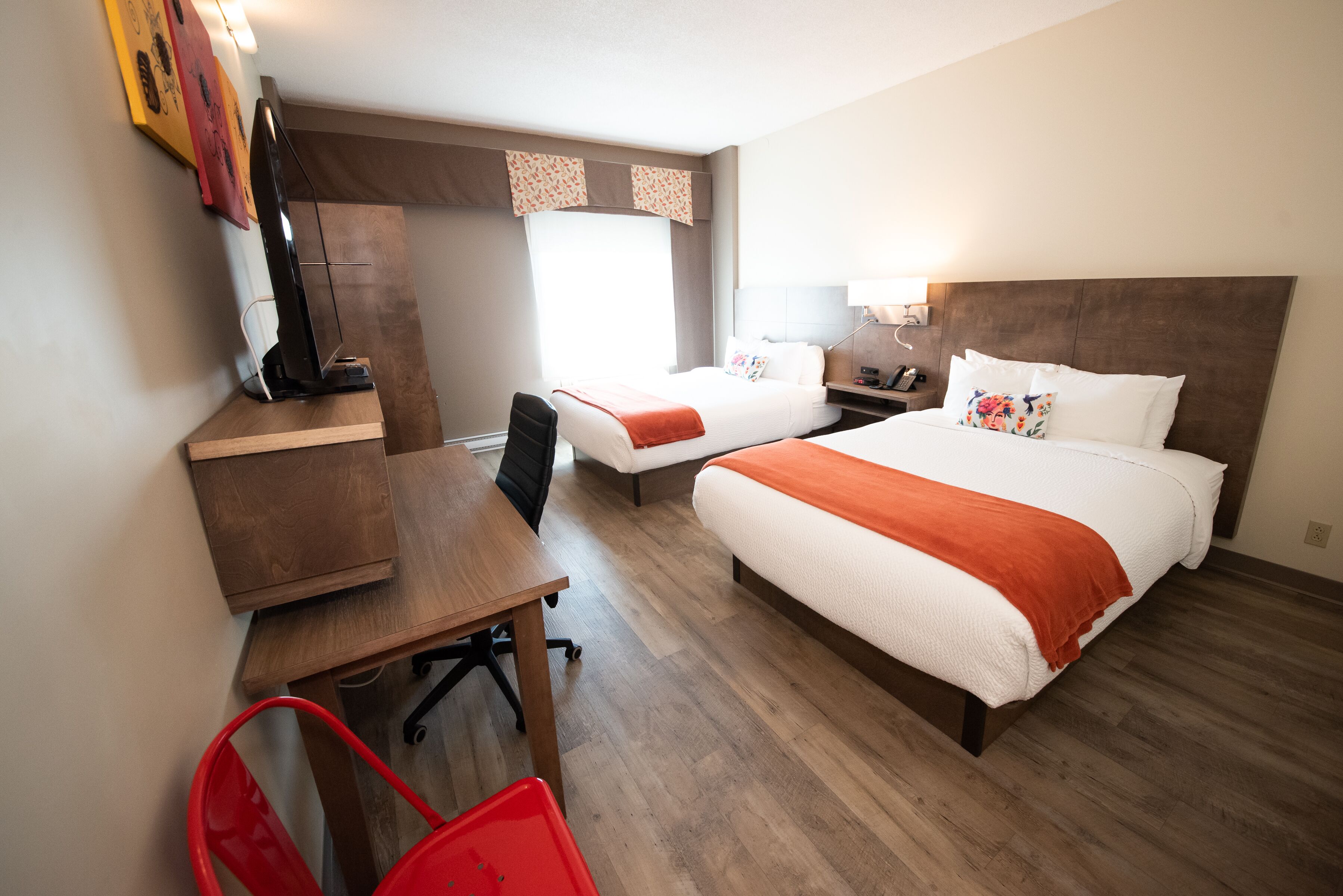 Una habitación de hotel con dos camas, un escritorio, una silla y un televisor.