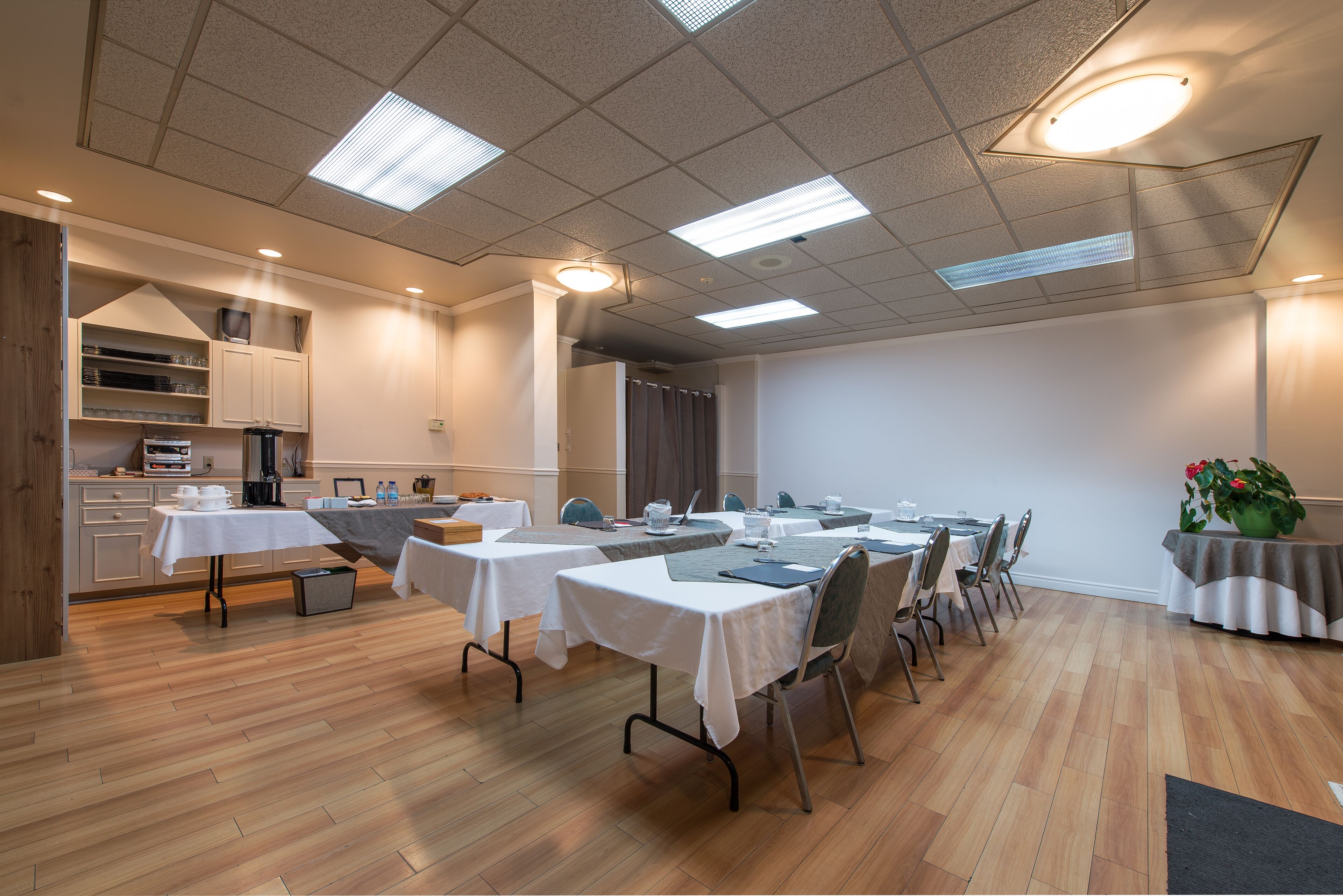 Una sala de conferencias con mesas, sillas y una zona de cocina.
