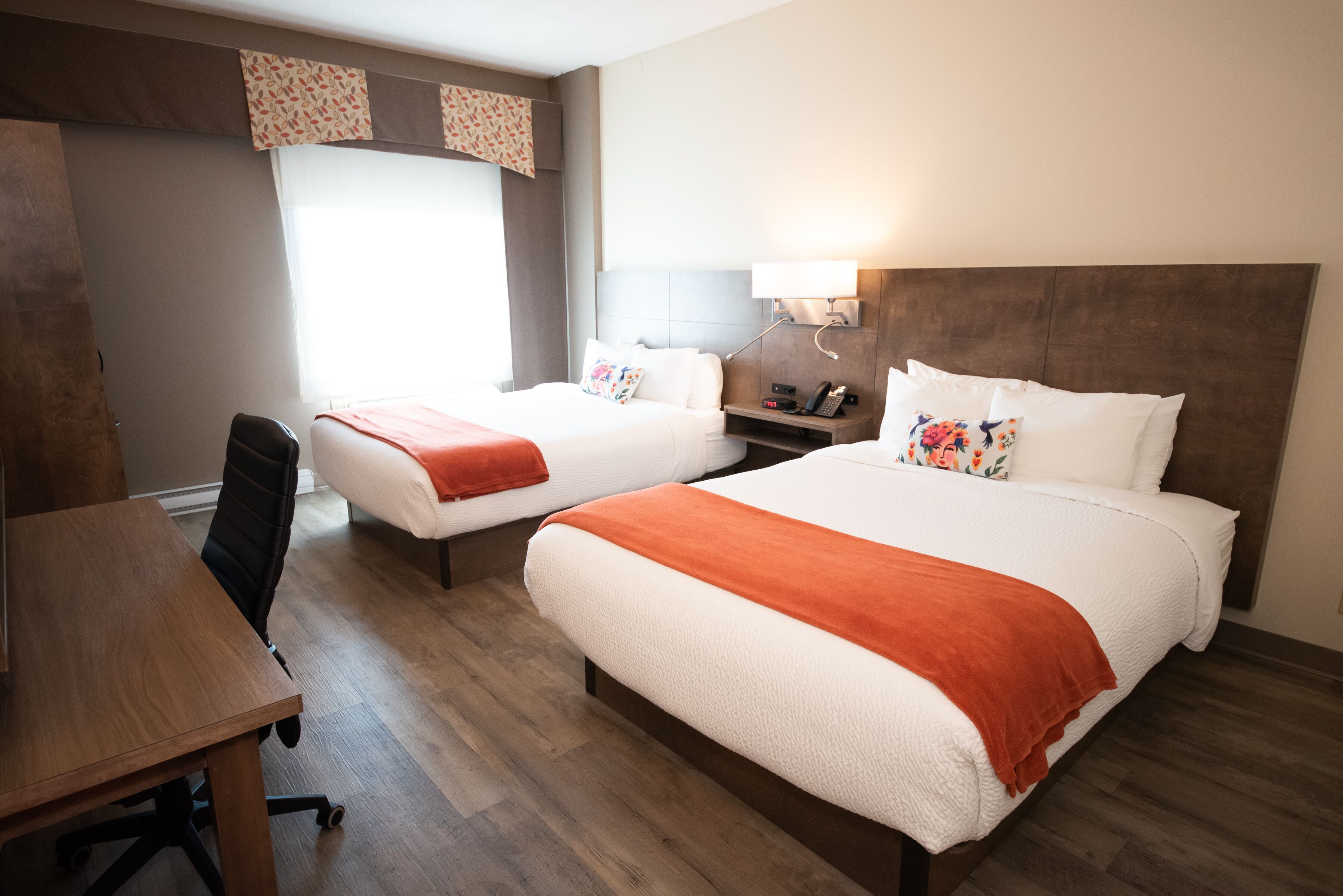 Une chambre d’hôtel avec deux lits, un bureau et une chaise.
