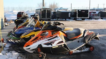 A parking lot with snowmobiles and trailers.