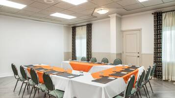A conference room with a long table, chairs, and a white ceiling with fluorescent lights.