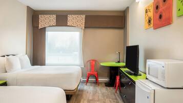 Una habitación de hotel con dos camas, un escritorio, un televisor, un microondas y un refrigerador.