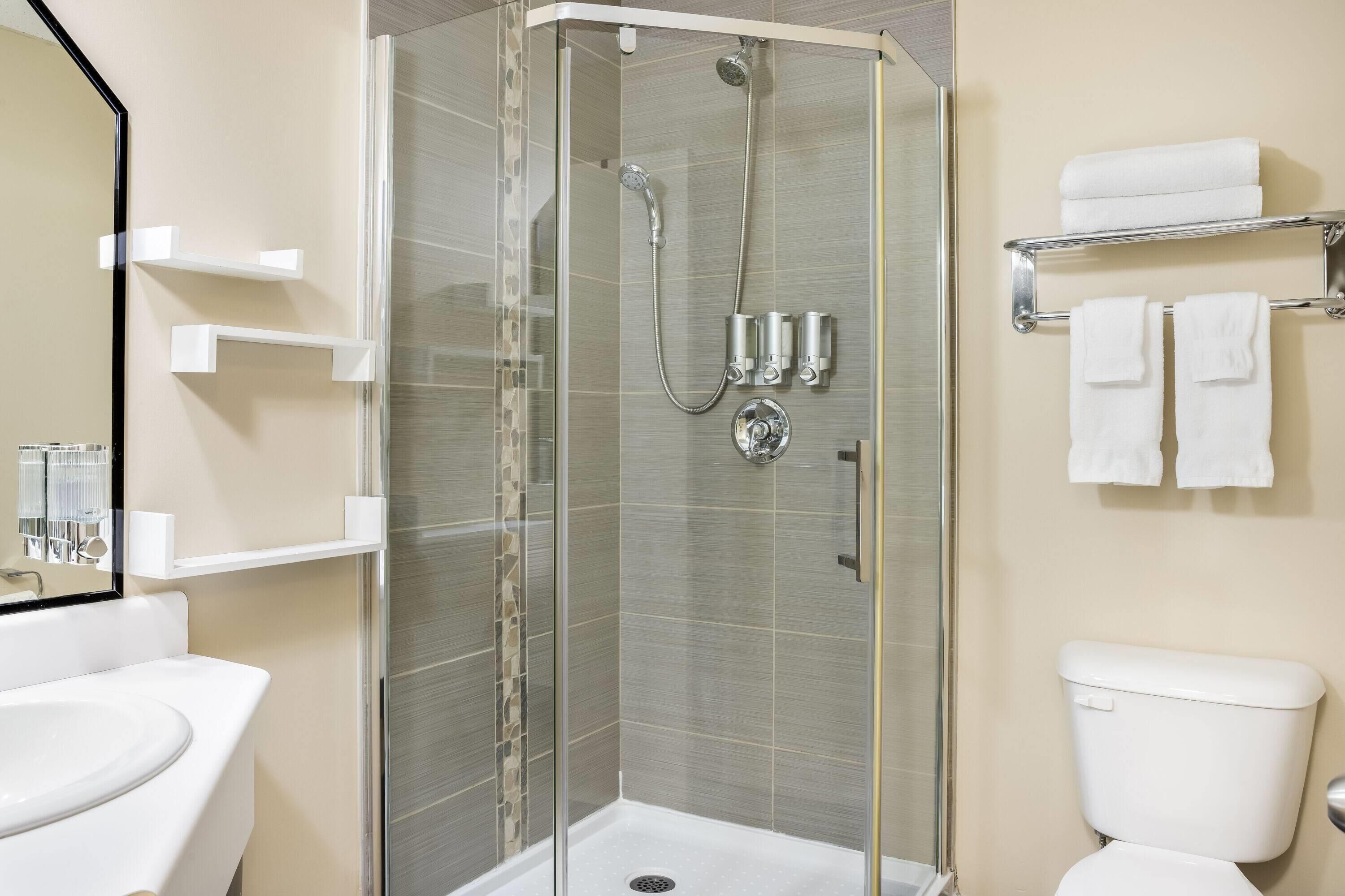 Une salle de bain moderne avec une douche à parois de verre, des toilettes blanches et un lavabo.