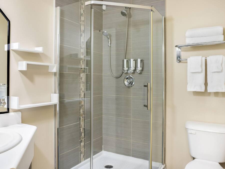 A modern bathroom with a glass-enclosed shower, a white toilet, and a sink.