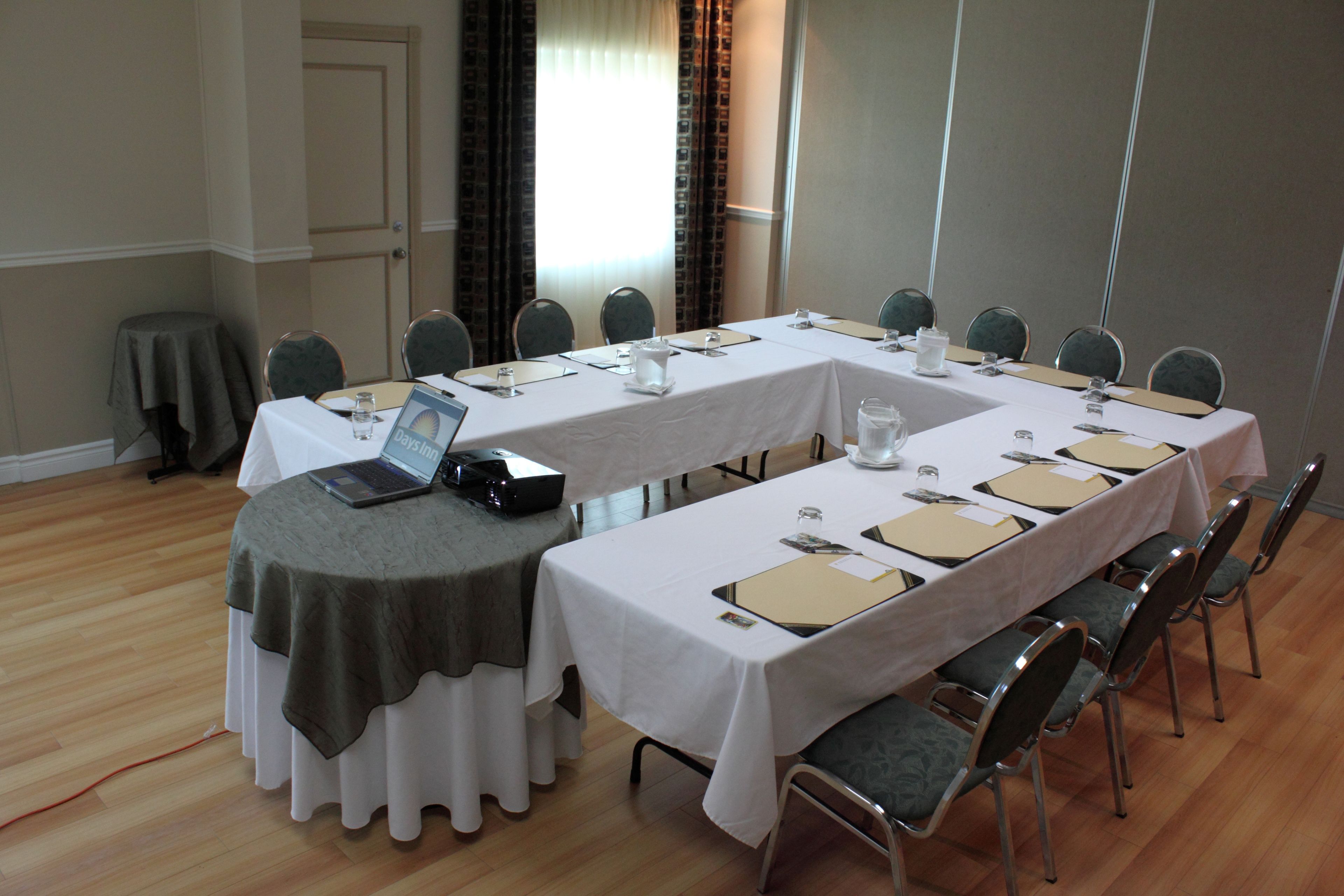 A conference room with a long table, chairs, and a laptop on one side.