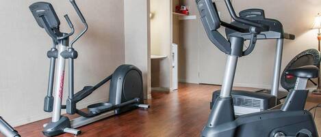Une salle de sport équipée de deux appareils elliptiques et d’un tapis de course.