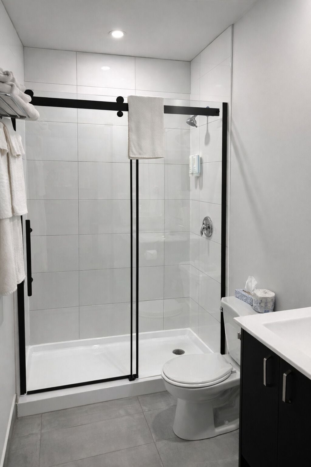 Un baño moderno con ducha de vidrio, inodoro y lavamanos con toallero.