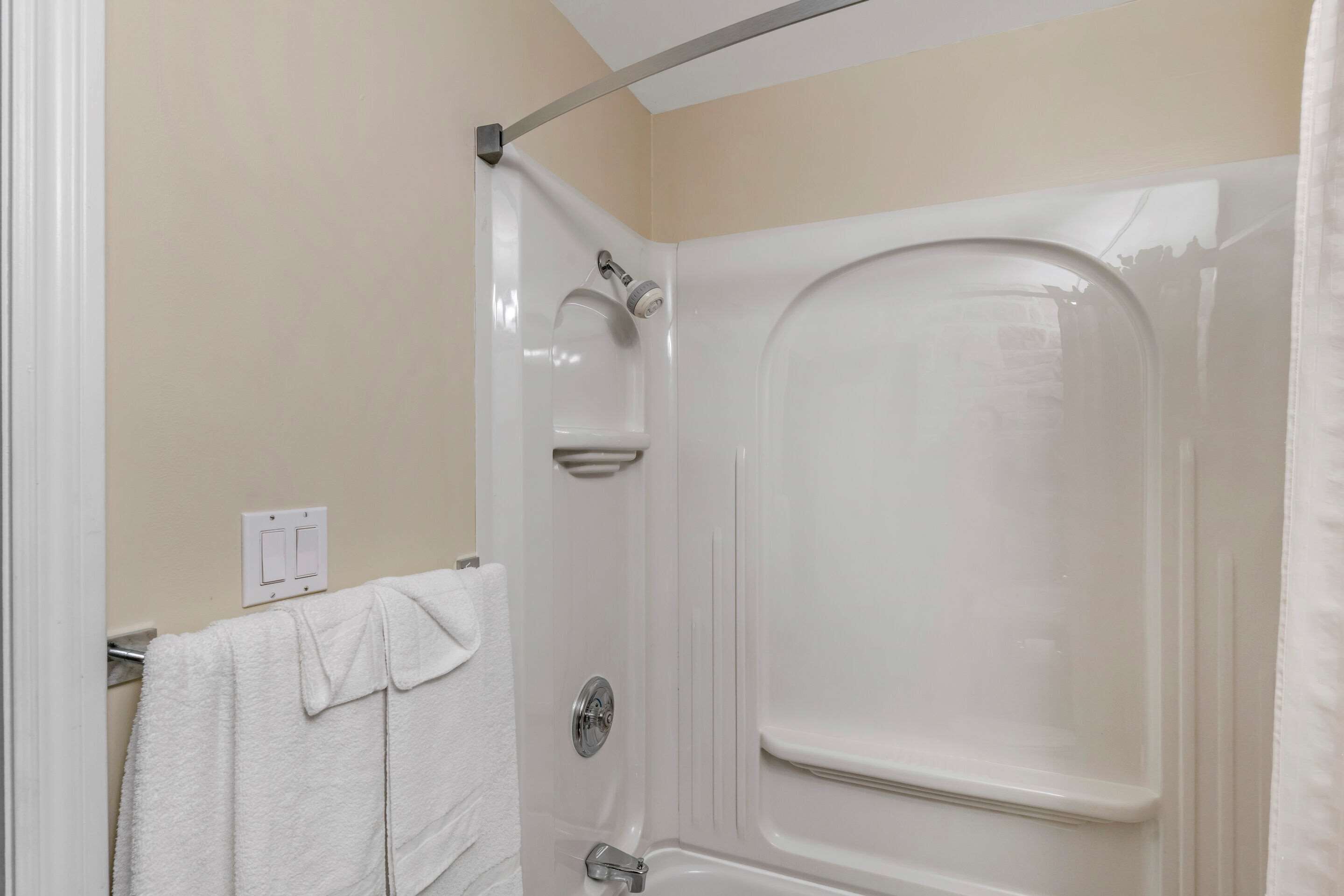 Une salle de bain avec une baignoire blanche, une pomme de douche et un porte-serviettes sur lequel est posée une serviette.