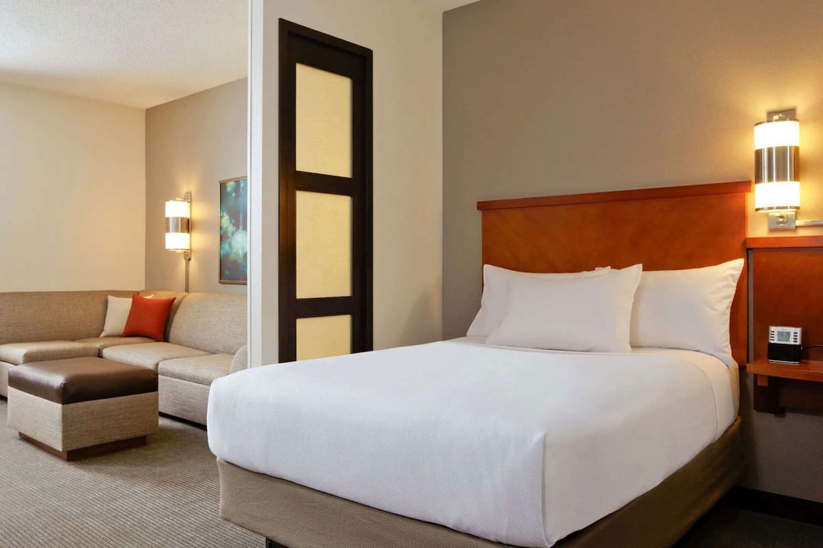 A hotel room with a bed, a sofa, a desk, and a nightstand.