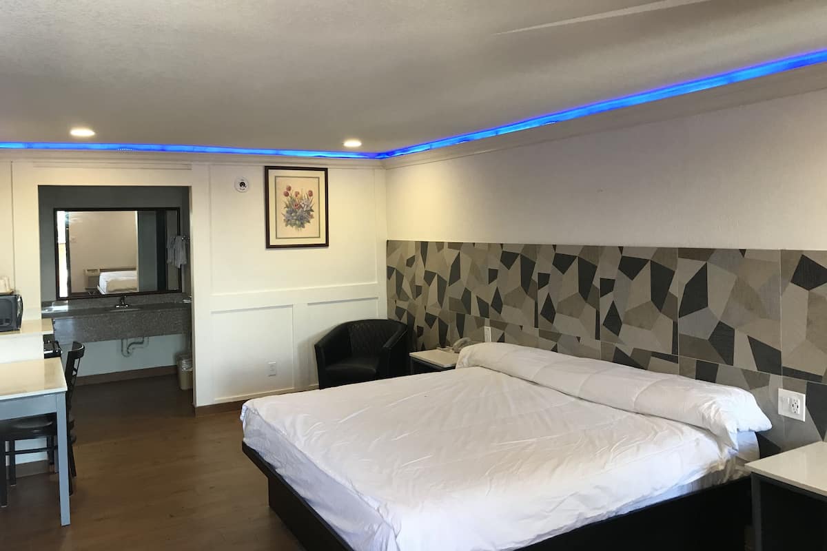 Una camera d'albergo con un letto, una scrivania, una sedia, uno specchio e una parete con motivo geometrico.