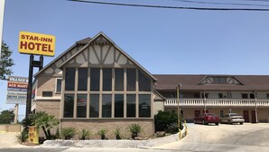 A Star-Inn Hotel with a large windowed front, a brick facade, and a parking lot with two cars.
