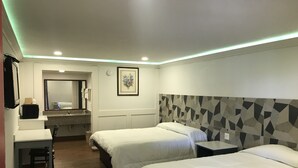 A hotel room with two beds, a desk, a chair, a vanity with a mirror, and a framed picture on the wall.