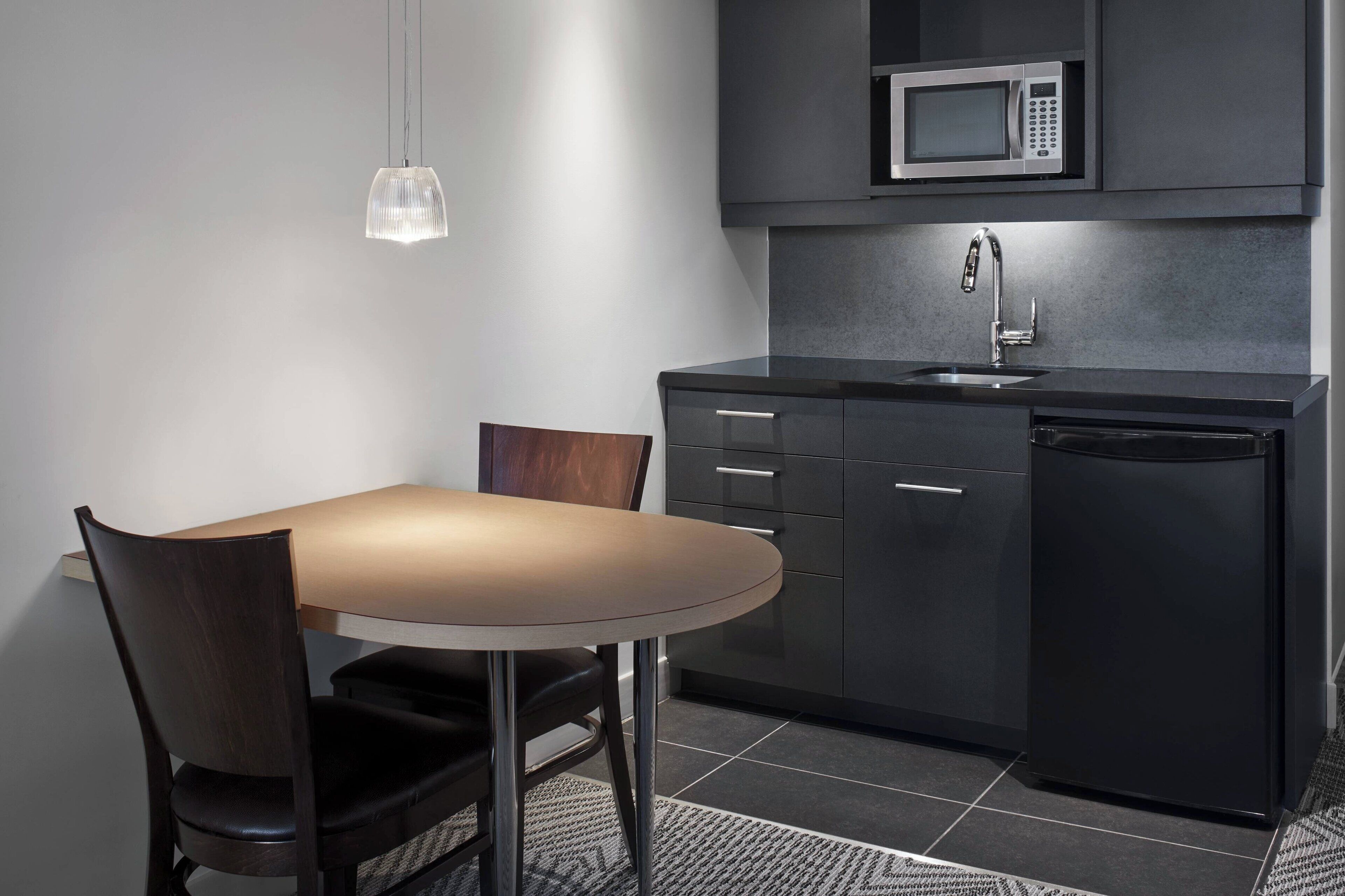 A modern kitchen with a dark countertop, a built-in microwave, a sink, and a dishwasher.