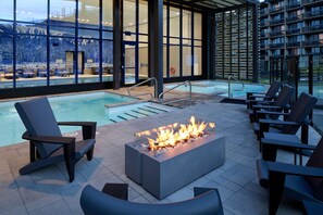 A modern outdoor pool area with a fire feature, lounge chairs, and a view of a snowy landscape. - Delta Hotels by Marriott, Mont Sainte-Anne, Resort & Convention Center (Beaupre)