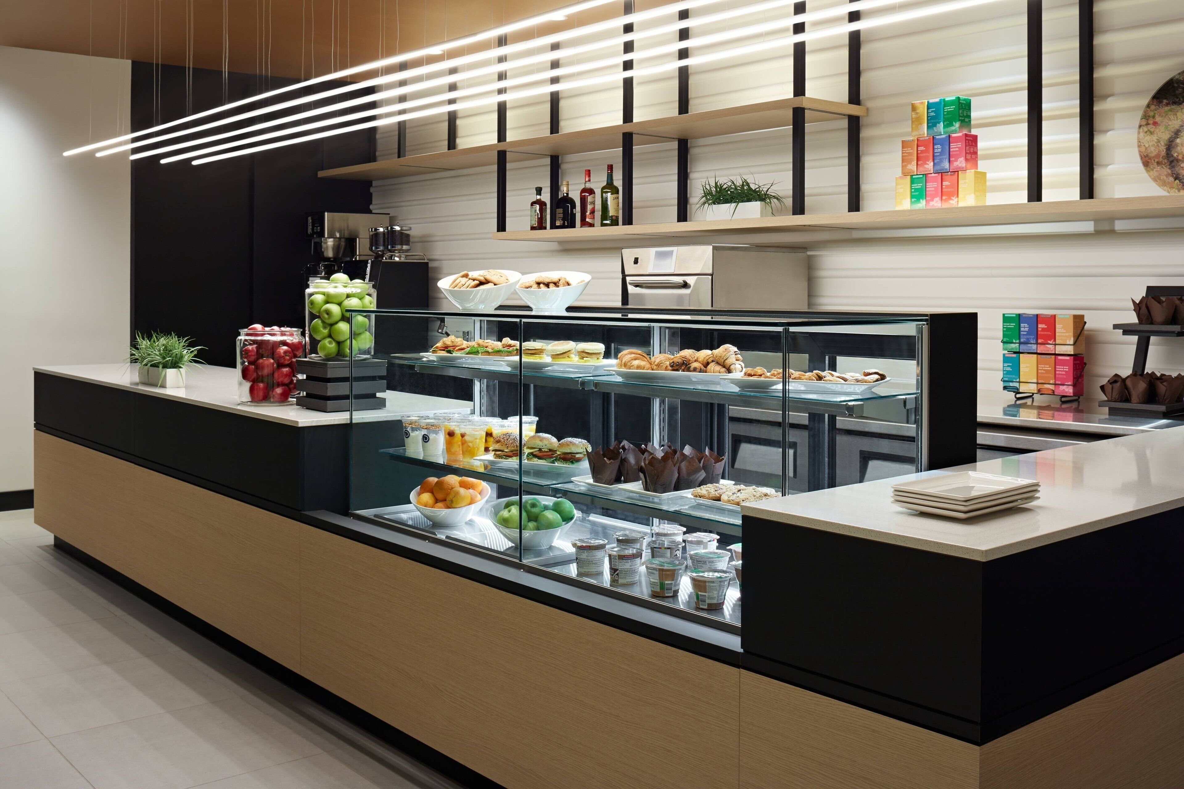 A modern breakfast bar with a variety of food items, including pastries, fruits, and beverages.