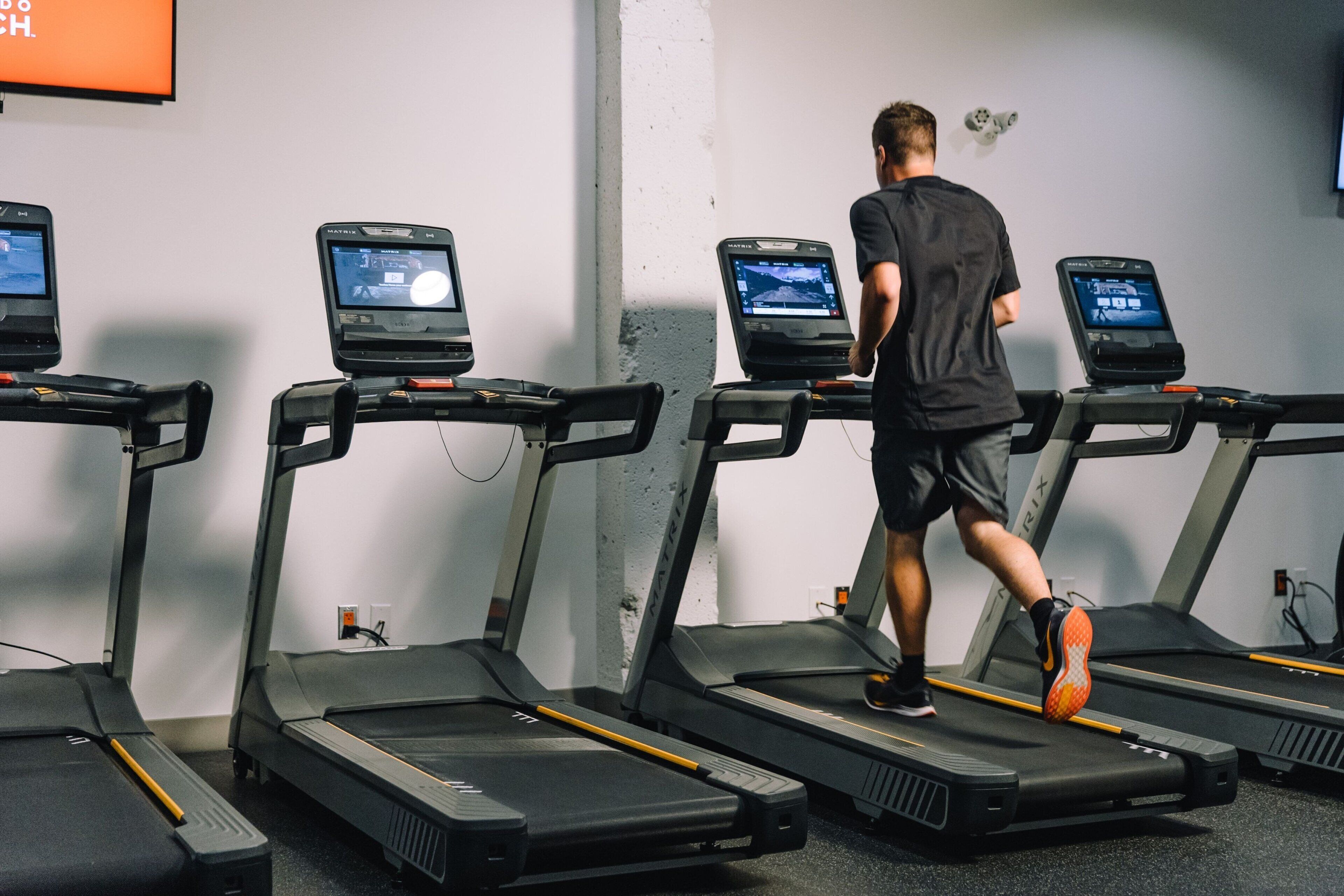 Ein Fitnessraum mit Laufbändern und einer Person, die auf einem läuft.