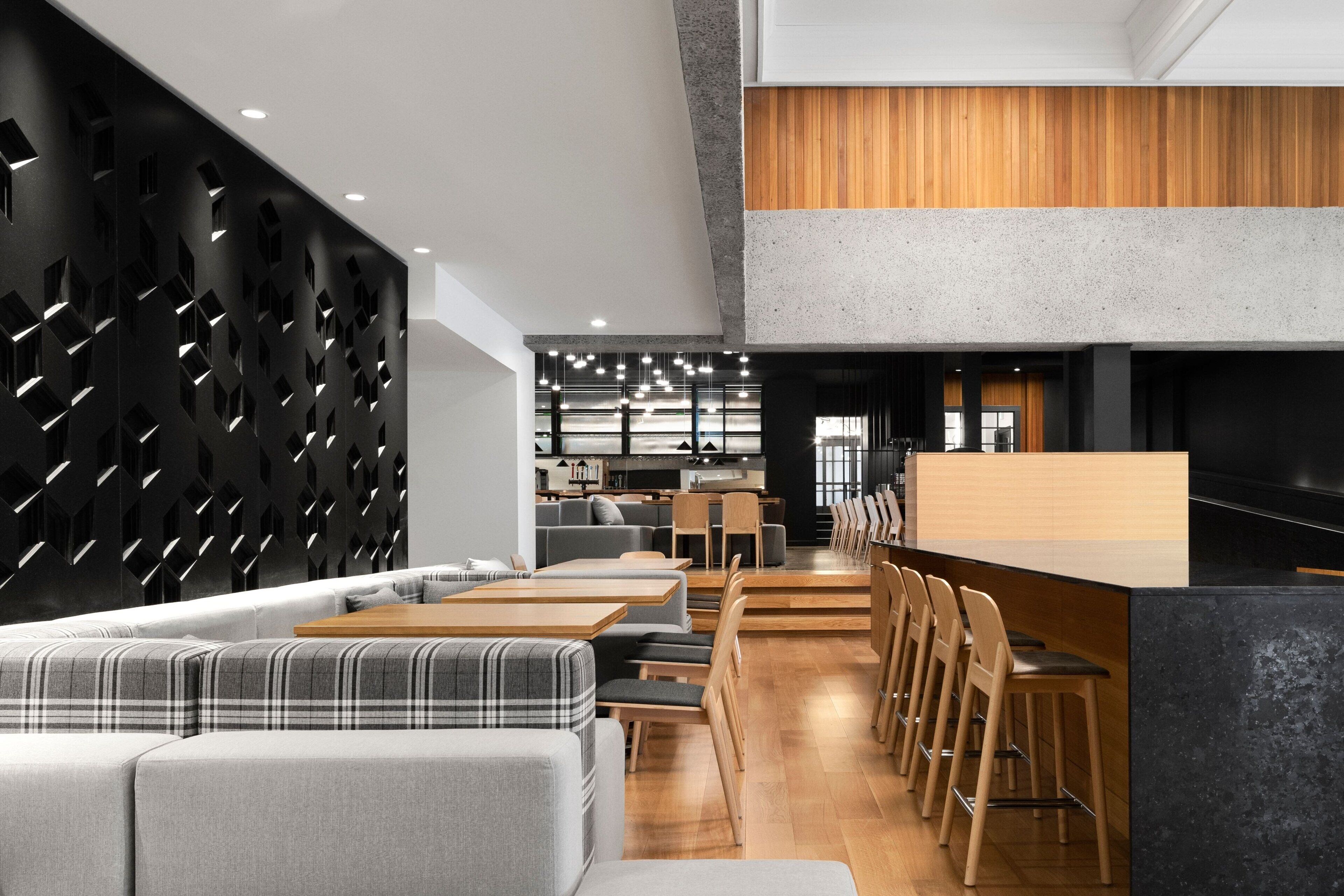A modern interior with a dining area featuring a long counter and multiple seating options, including a sofa and chairs.