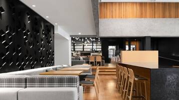Un intérieur moderne avec un espace repas comprenant un long comptoir et plusieurs options d’assises, notamment un canapé et des fauteuils.