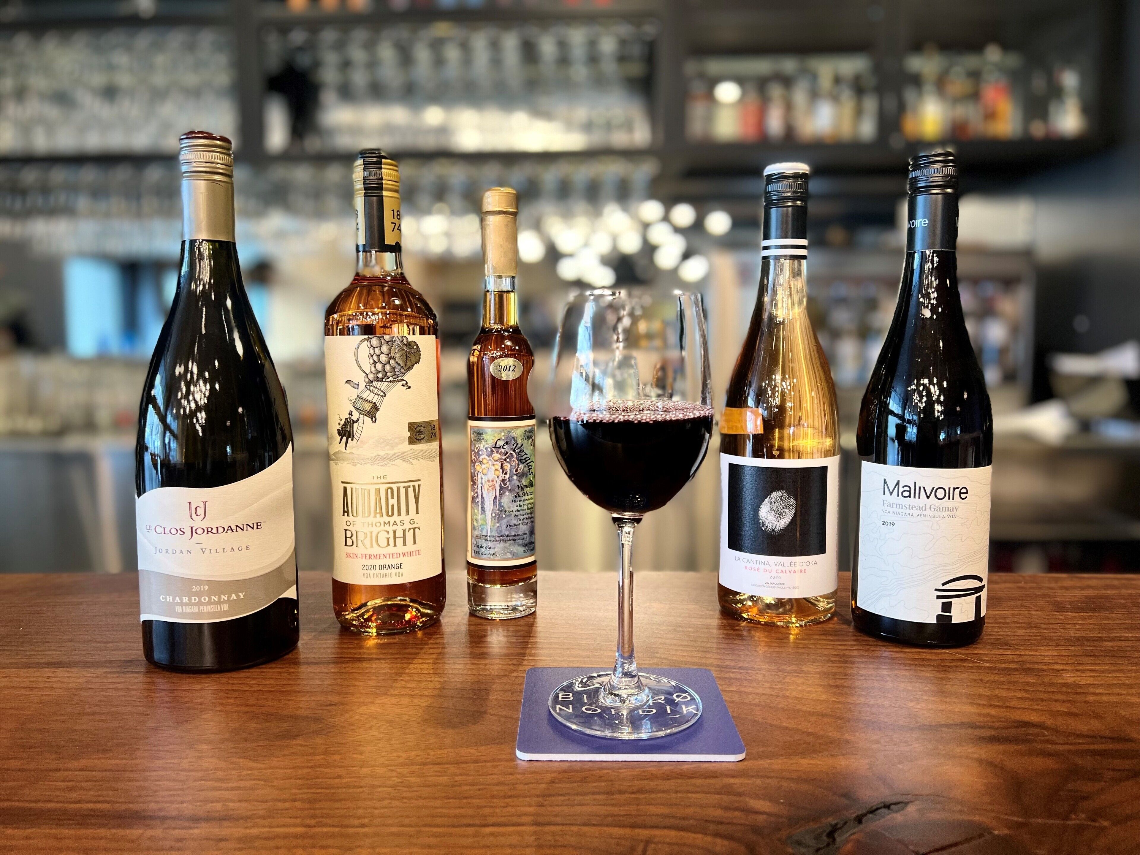 Une sélection de bouteilles de vin et un verre de vin rouge sur une table en bois.
