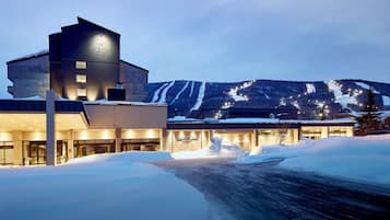 A hotel with a modern design, a snow-covered landscape, and a mountain in the background.