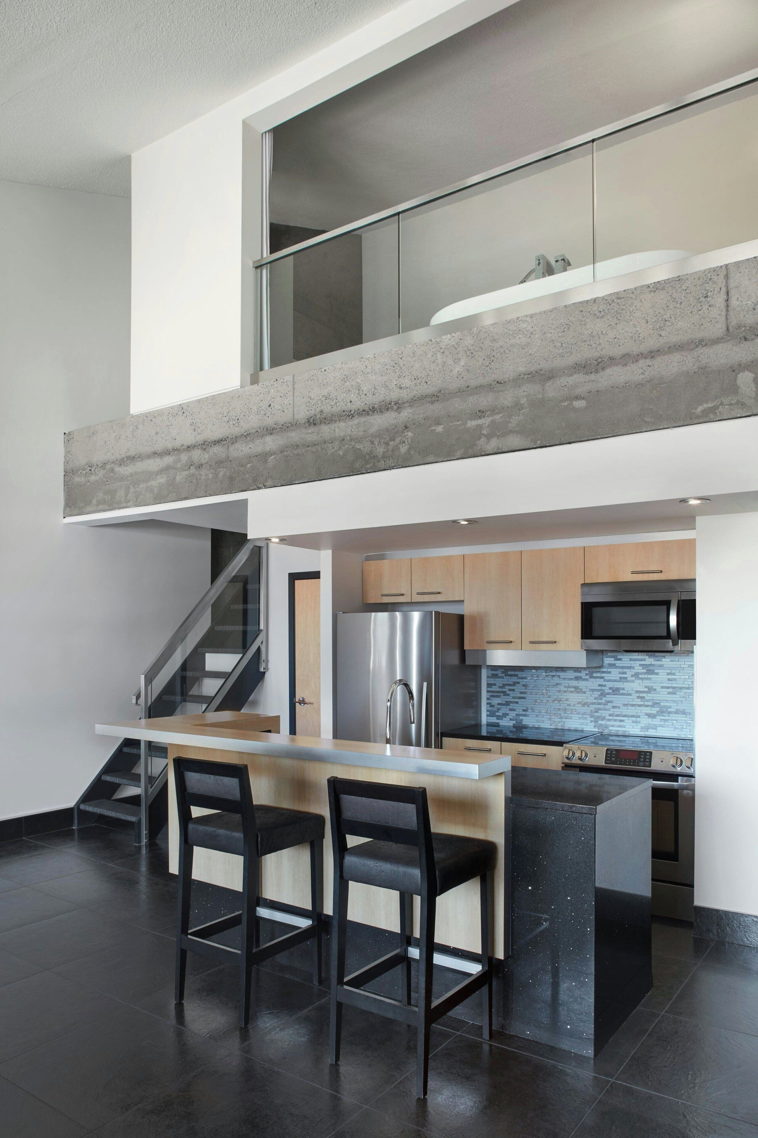 A modern kitchen with a central island, stainless steel appliances, and a mezzanine level.
