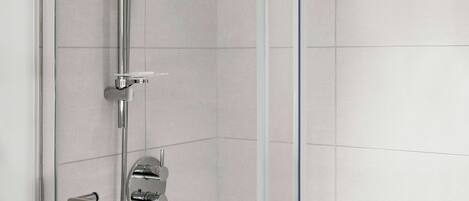 Eine moderne Dusche mit Glasabtrennung, Chromarmaturen und Bedienfeld.