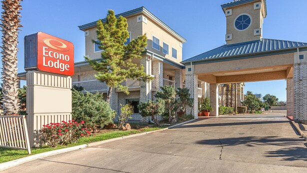 Ein Hotel Eingang mit einem Schild für Econo Lodge, einem überdachten Parkplatz und einem Uhrturm.
