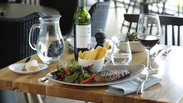 Une table dressée pour le dîner, avec un steak, des frites, une salade et une bouteille de vin.